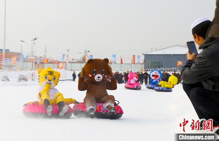 圖為臨夏市南龍鎮(zhèn)馬家莊村舉辦的鄉(xiāng)村文化旅游節(jié)上，游客穿著卡通服裝在體驗(yàn)雪上飛碟項(xiàng)目。近年來(lái)，臨夏州形成了“春賞花、夏避暑、秋摘果、冬玩雪”的全季節(jié)旅游產(chǎn)品體系。(資料圖) 高展 攝