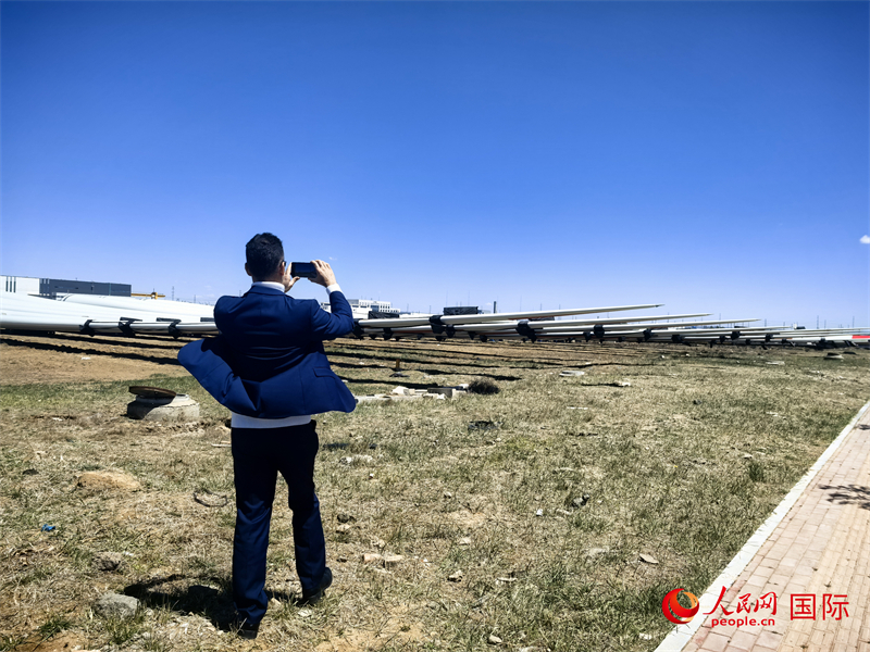 外媒記者拍攝廠房外的風力渦輪發電機的巨型漿葉。人民網 楊春燕攝